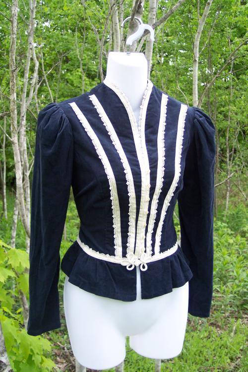 on a dress maker's dummy, a blue velvet mutton sleeve top with lines of white lace.